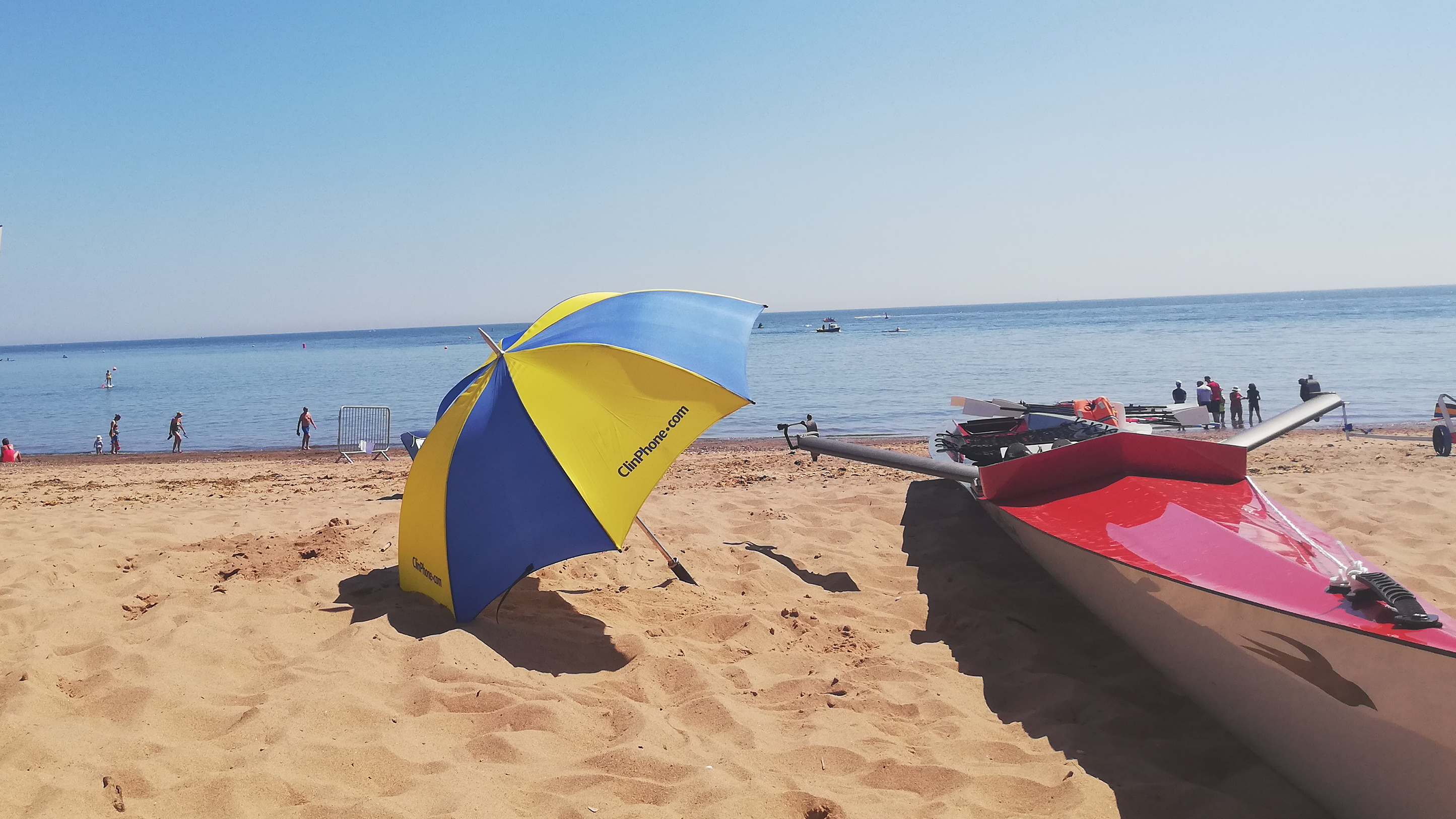 a coastal rowing boat on a beach with a beach umbrella