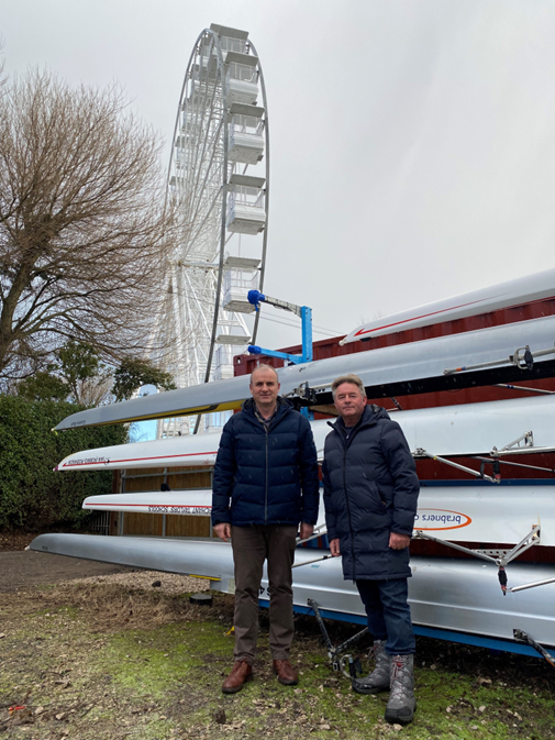 2 men by rowing boats and ferris wheel