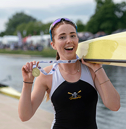 Girl with gold medal carrying boat