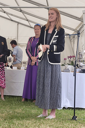 Woman in blazer giving speech in front of trophies