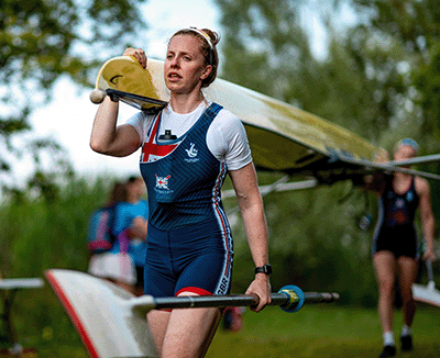 woman in GB kit carrying boat