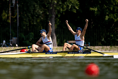 Men's pair with arms in air after crossing the finish line first