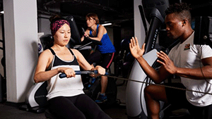 man coaching woman on indoor rower