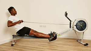 Man on indoor rower in room with cream walls