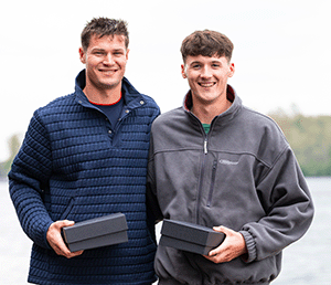 2 male athletes with trophies in boxes