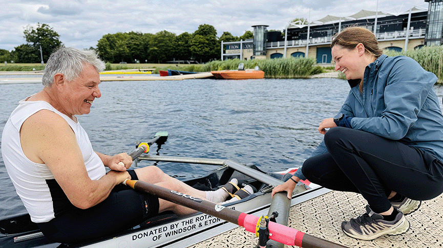Female coach holding rigger of single sculler