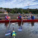 Four people in a touring boat with another in the background
