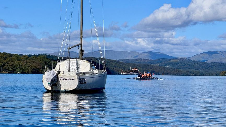 A sail boat in the fore ground with an explore boat in the distance