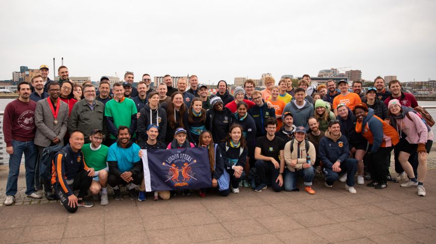 The whole london otters club posing for a picture with their club flag