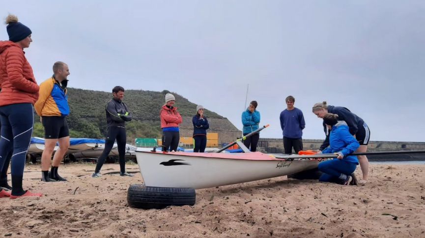 People gathered round a coastal single watching and listening to coaching