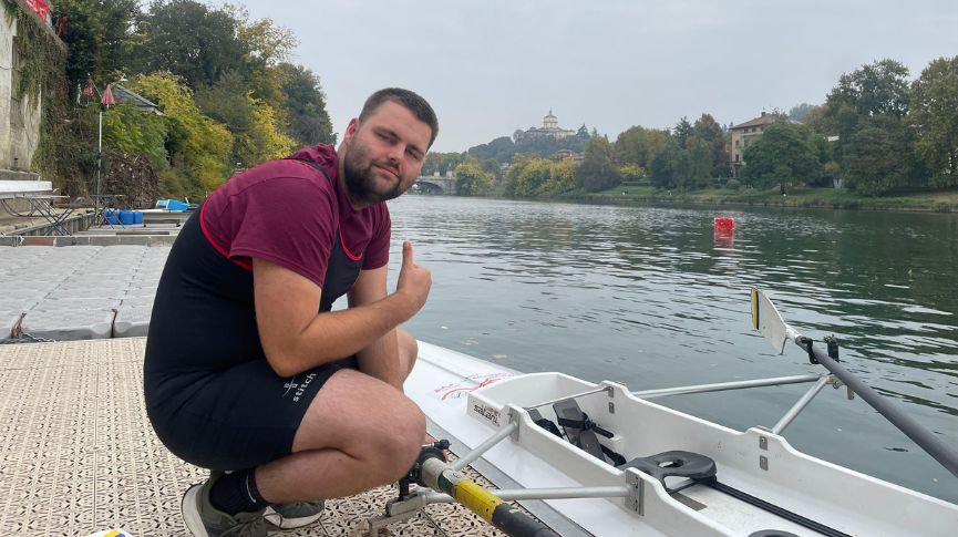 A rower posing on the landing stage next to a boat