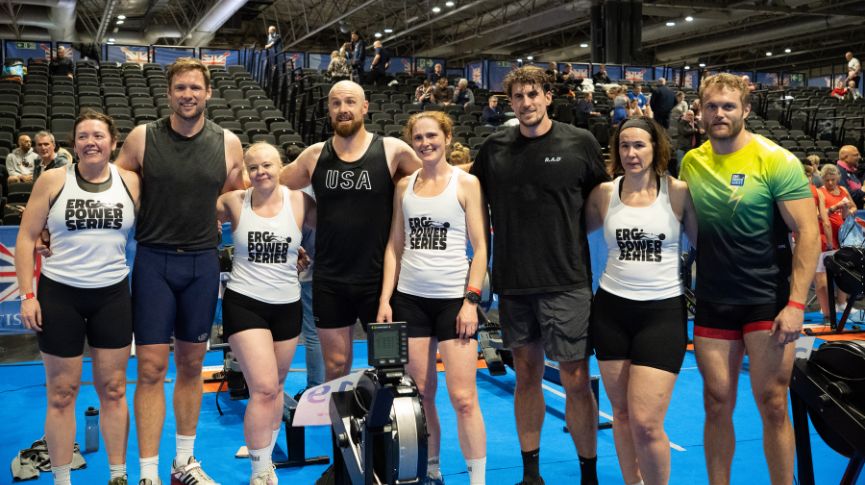 eight rowers standing in front of rowing machines after winning relay races