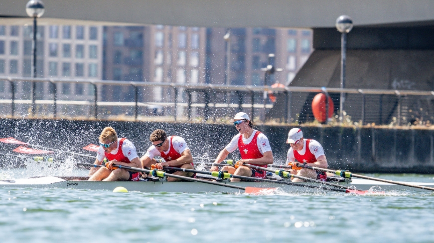 Four rowers in red celebrating on the water