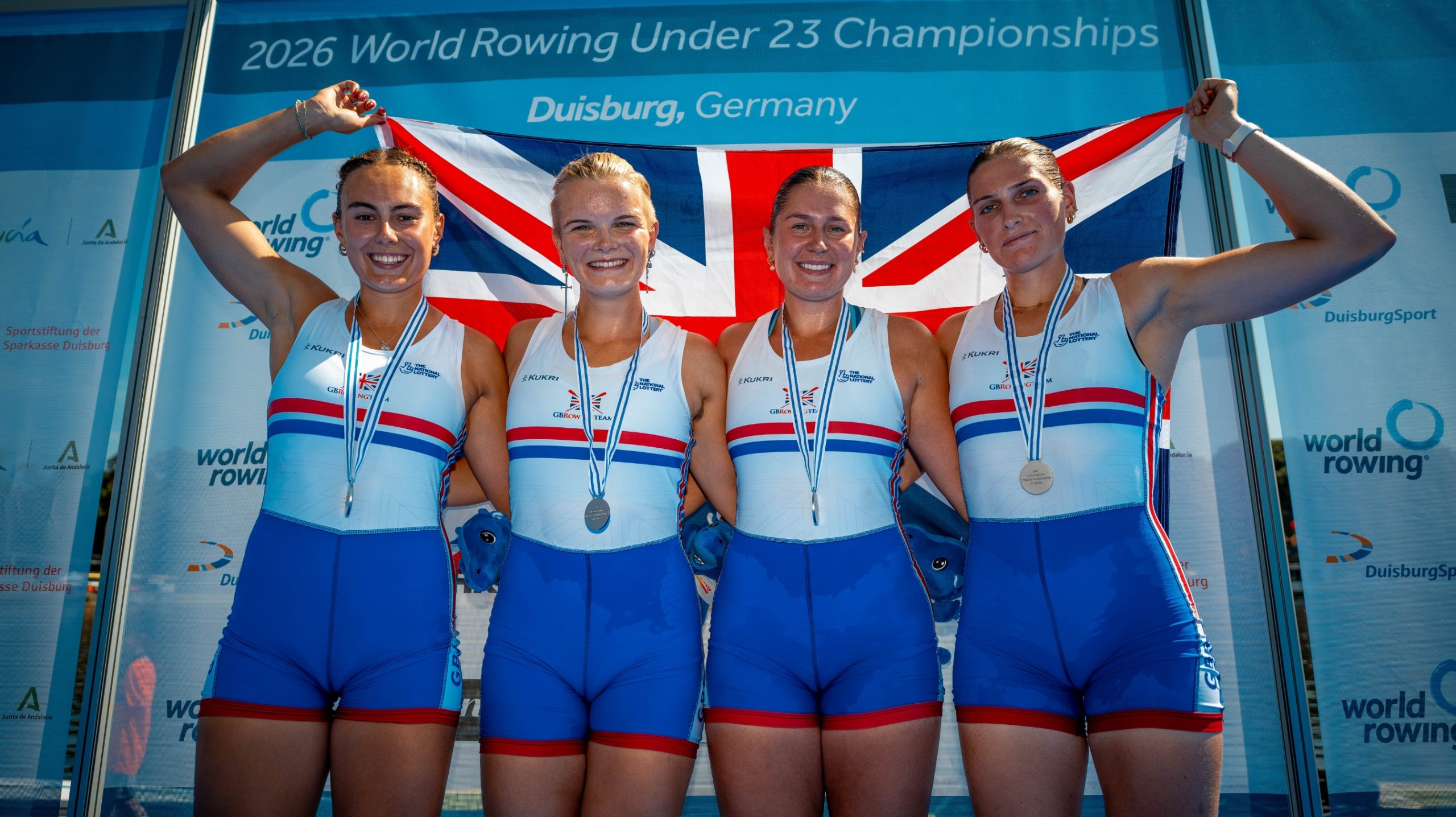 The Women's Four with medals and British flag